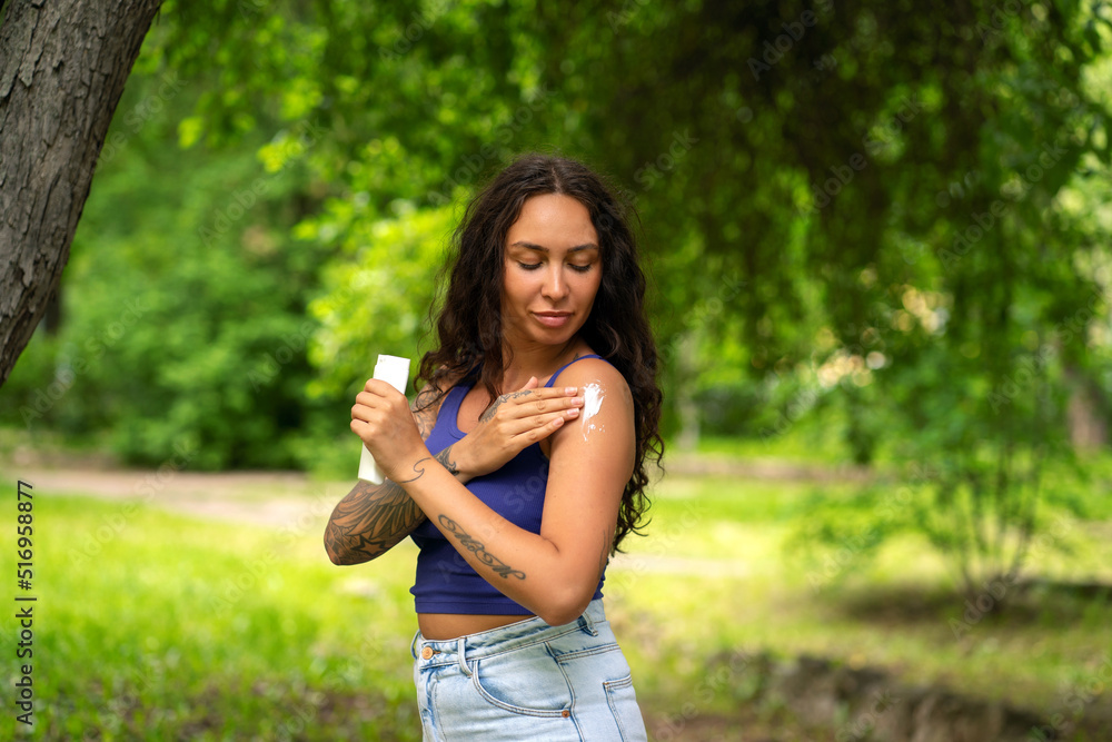 Beautiful girl smears herself with sunblock in the park. Skin protection from the sun. Beautiful girl smears herself with sunblock in the park. Skin protection from the sun.