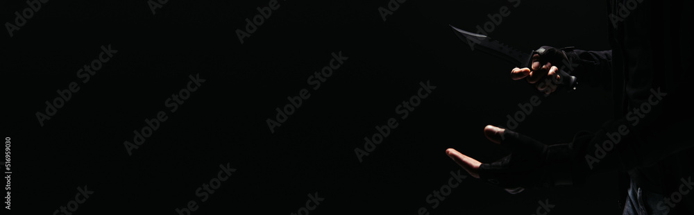 Cropped view of african american bandit holding knife isolated on black, banner Cropped view of african american bandit holding knife isolated on black, banner