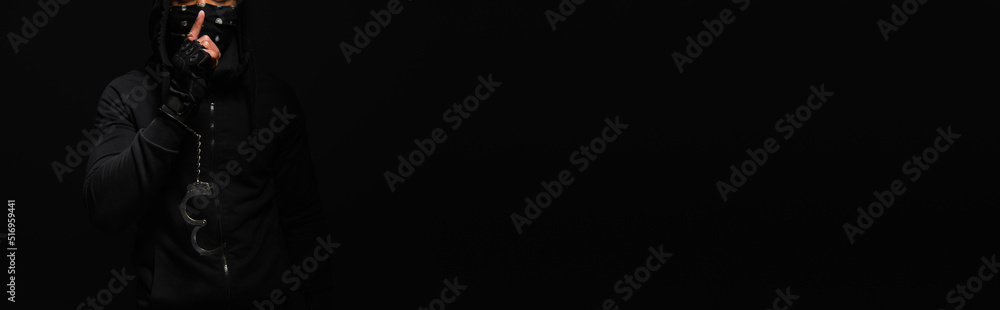 Cropped view of african american bandit in handcuff showing secret gesture isolated on black, banner - obrazy, fototapety, plakaty 