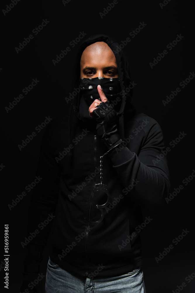 African american bandist in mask on face and handcuffs showing secret gesture isolated on black African american bandist in mask on face and handcuffs showing secret gesture isolated on black