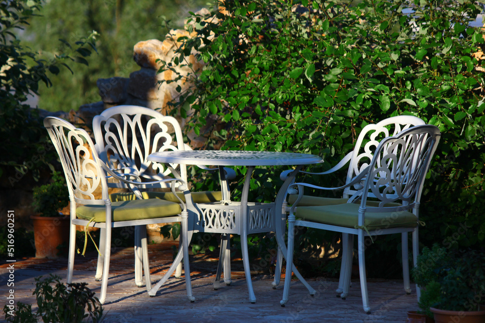 Obraz premium White retro table and chairs in the garden. Garden arrangement. Garden furniture