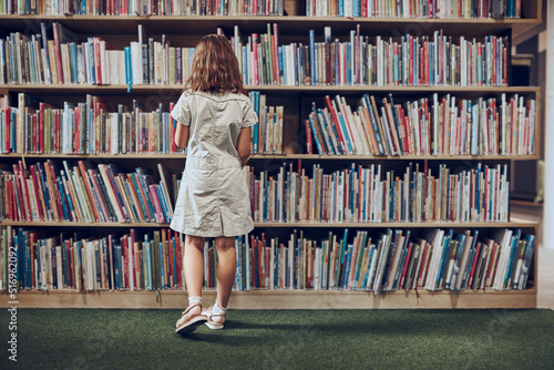 Schoolgirl choosing book in school library. Smart girl selecting literature for reading. Learning from books. Benefits of everyday reading. Child curiosity