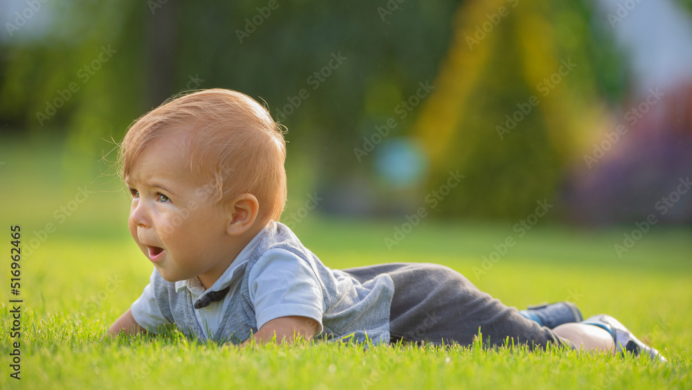 A cheerful and happy little boy is sitting on a green lawn. A cheerful and happy little boy is sitting on a green lawn.