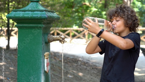 Obraz na płótnie 8-year-old child drinks and refreshes himself with water from the fountain - record heat hot day in summer with temperatures over 40 degrees - Global warming and climate Change in Milan w salonie
