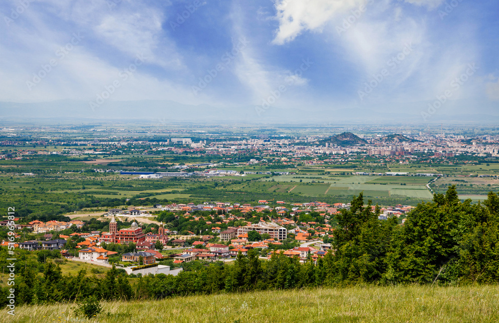 Town Plovdiv with houses and fields against backdrop of Rhodope Mountains and hills covered with forests and cloudy sky