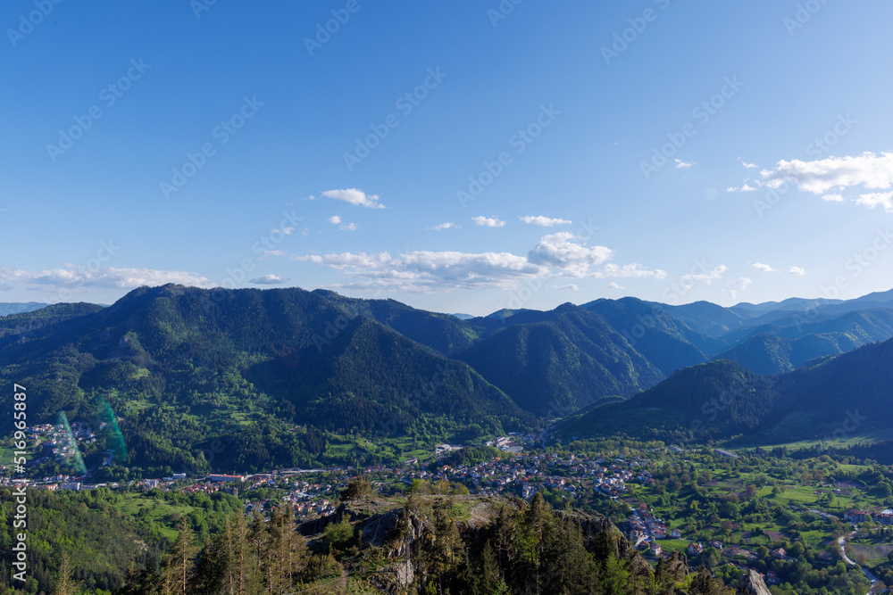 View from rock to town of Smolyan with meadows for cattle walking and houses between mountain range of Rhodope Mountains