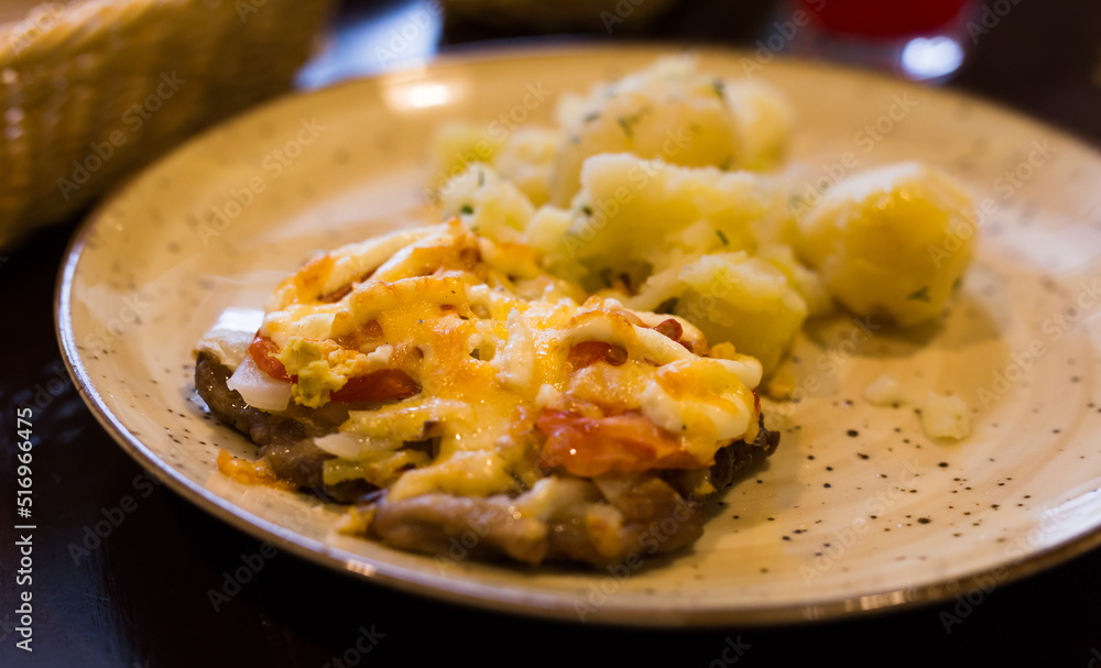 meat baked with cheese with boiled potatoes served on a plate in restaurant meat baked with cheese with boiled potatoes served on a plate in restaurant