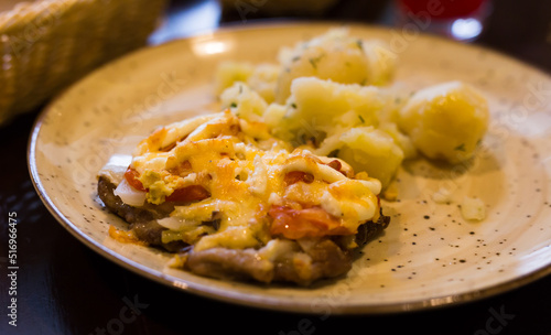 meat baked with cheese with boiled potatoes served on a plate in restaurant
