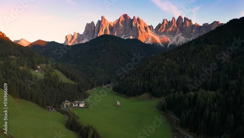 Val Di Funes, Dolomites, Italy - 4K Flying towards and descending at St. Johann Church (Chiesetta di San Giovanni in Ranui) in South Tyrol with the Italian Dolomites at background  photo