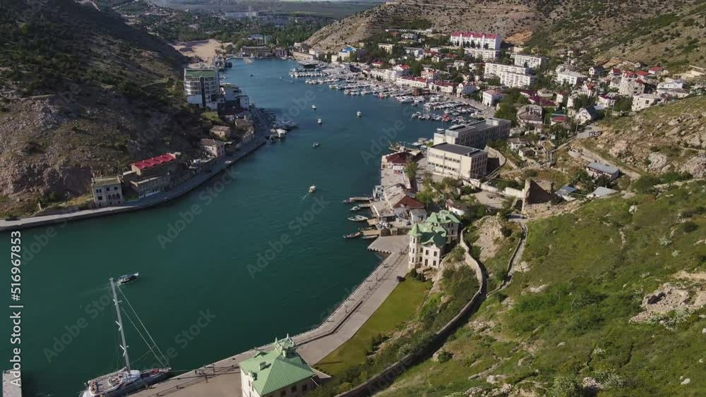 Flight over the Balaklava Bay the ruins of the ancient Genoese fortress. Yachts, boats, ships are sailing. Resort heavenly city, waterfront, tourist attraction. Seascape. Tourist attractions of Crimea Flight over the Balaklava Bay the ruins of the ancient Genoese fortress. Yachts, boats, ships are sailing. Resort heavenly city, waterfront, tourist attraction. Seascape. Tourist attractions of Crimea