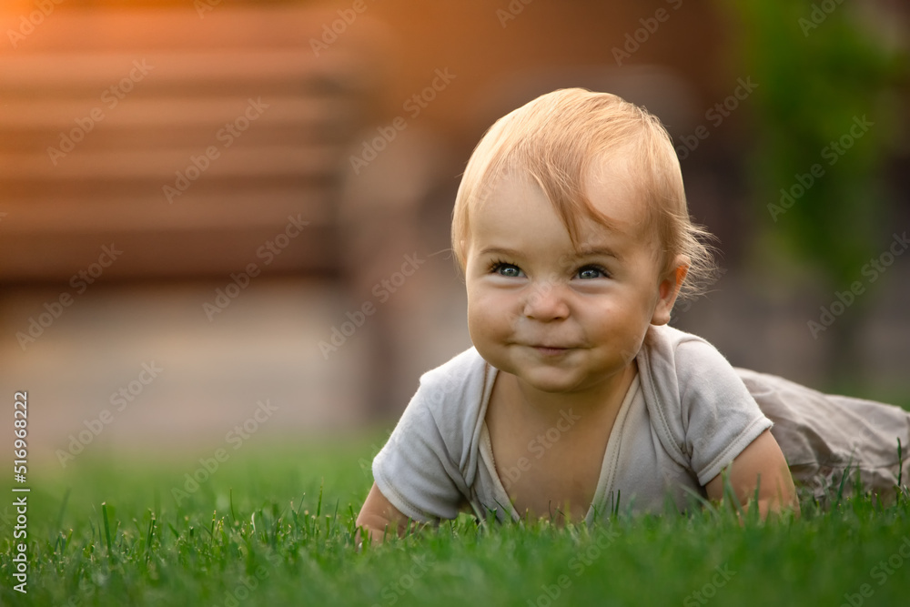 A cheerful and happy little boy is sitting on a green lawn. A cheerful and happy little boy is sitting on a green lawn.