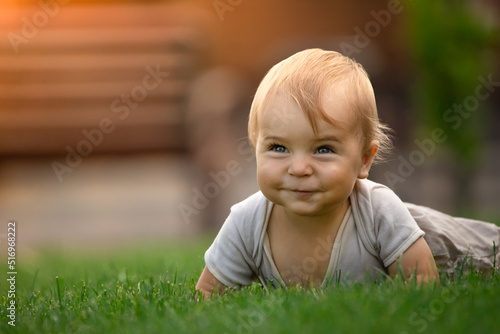 A cheerful and happy little boy is sitting on a green lawn.