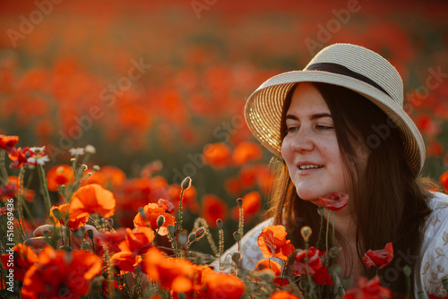 Scenic picturesque of beautiful girl in white and beige dress and straw hat in poppy field at sunset, Portrait of romantic young woman with flowers, body positivity, Selective focus natural light © AnnaRudnitskaya