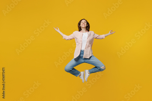Full body spiritual tranquil young woman she 30s in striped shirt white t-shirt hold spreading hands in yoga om aum gesture relax meditate try to calm down isolated on plain yellow background studio