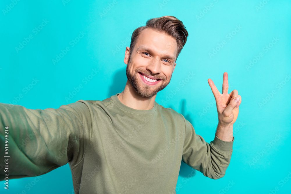 Fototapeta premium Photo of funny influencer man take selfie show v-sign shiny smile wear pullover isolated blue color background
