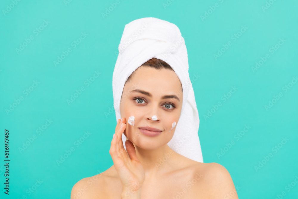 positive young lady apply face cream on blue background