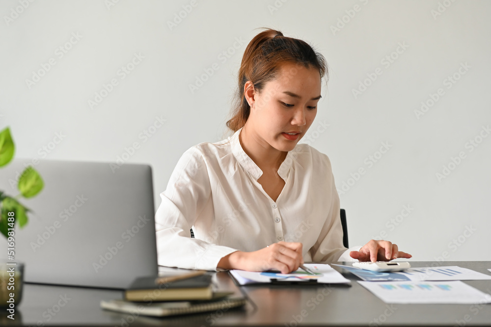 Asian businesswoman using calculator and laptop for do math finance in office and business, tax, accounting, statistics and analytic research concept. Asian businesswoman using calculator and laptop for do math finance in office and business, tax, accounting, statistics and analytic research concept.