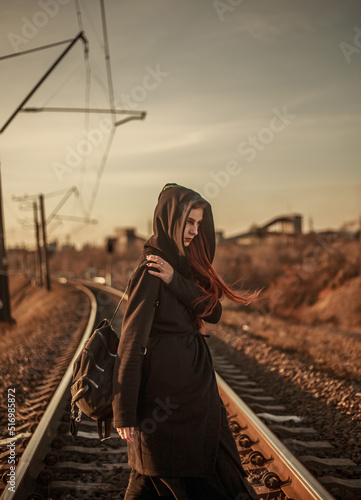 Young lonely woman walking along railway track, on background of industrial city, despair and depression portrait,  in dramatic and anti-utopia style © okostia