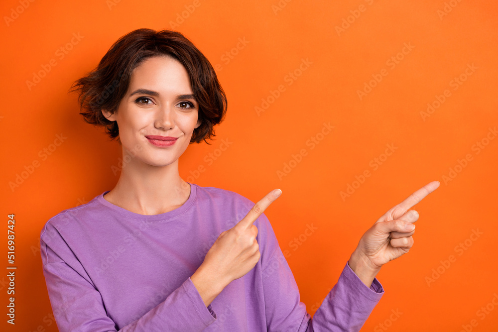 Photo of shiny pretty girl dressed purple pullover pointing empty space isolated orange color background Photo of shiny pretty girl dressed purple pullover pointing empty space isolated orange color background