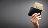 Businessman holding dollars with wallet.