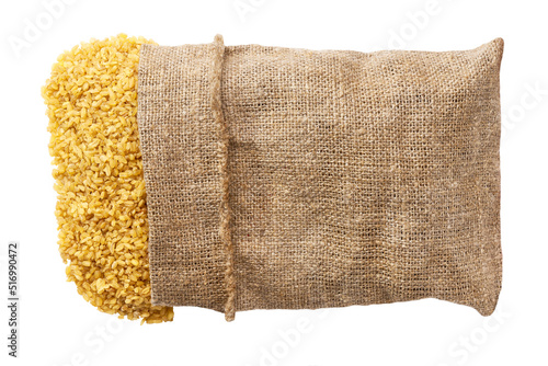 Organic bulgur in sack isolated on white background flat lay. Grains are scattered out of the bag top view.