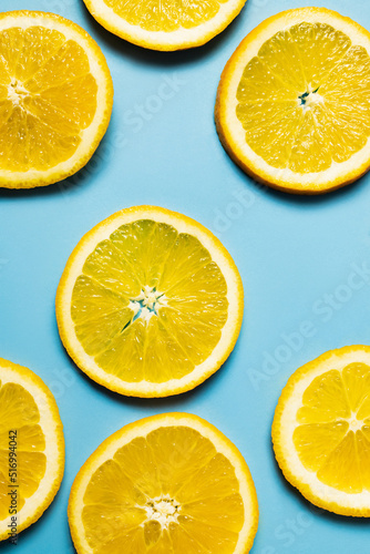 Top view of natural orange slices on blue background.