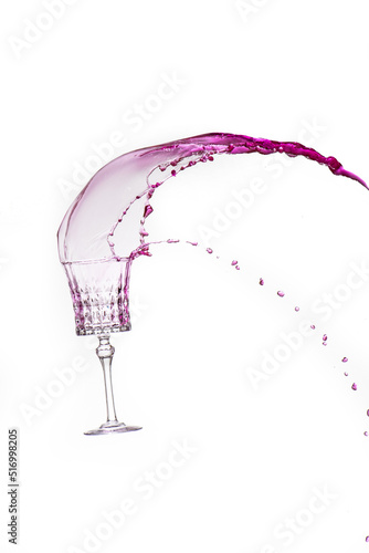 Glass in motion with pink coloured liquid splashing out of it