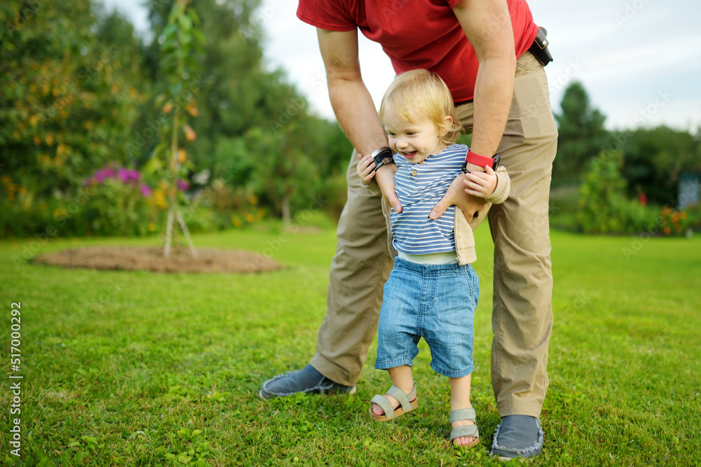 Cute toddler boy in his fathers arms. Dad and son having fun on sunny autumn day. Cute toddler boy in his fathers arms. Dad and son having fun on sunny autumn day.
