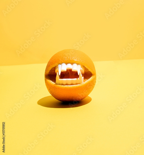 Valokuva An orange fruit and plastic vampires teeth, creative layout