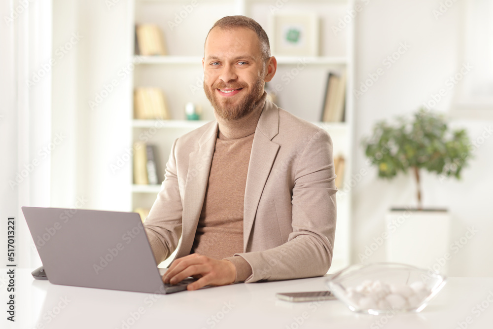Man sitting in front of a laptop computer at home and smiling Man sitting in front of a laptop computer at home and smiling