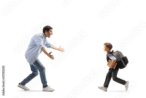 Full length profile shot of a schoolboy running to hug his father