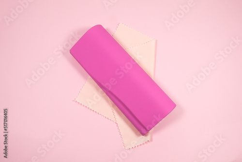 Pink frame womens glasses with glasses cleaning cloth and case on a pink background.