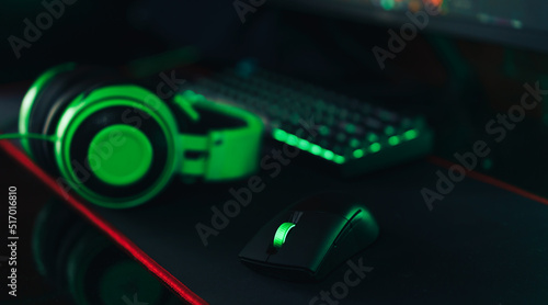 Gaming wireless accessories with green backlight next to headphones.