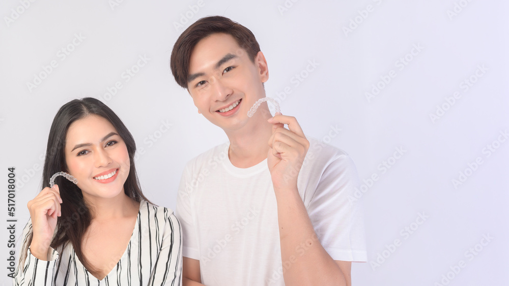 Young smiling man amd woman holding invisalign braces over white background studio, dental healthcare and Orthodontic concept.. Young smiling man amd woman holding invisalign braces over white background studio, dental healthcare and Orthodontic concept..
