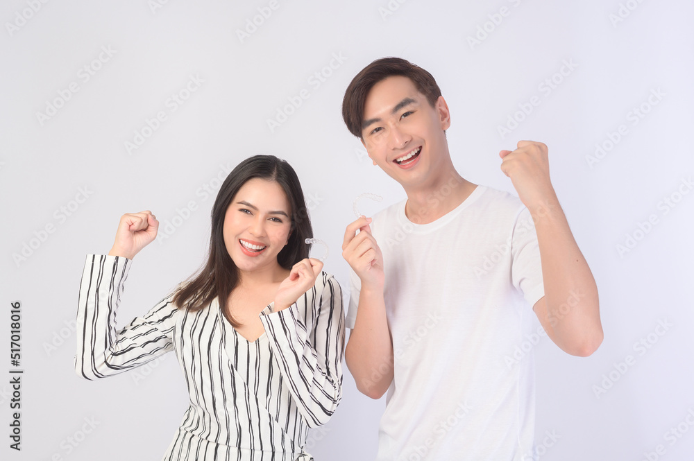 Young smiling man amd woman holding invisalign braces over white background studio, dental healthcare and Orthodontic concept.. Young smiling man amd woman holding invisalign braces over white background studio, dental healthcare and Orthodontic concept..
