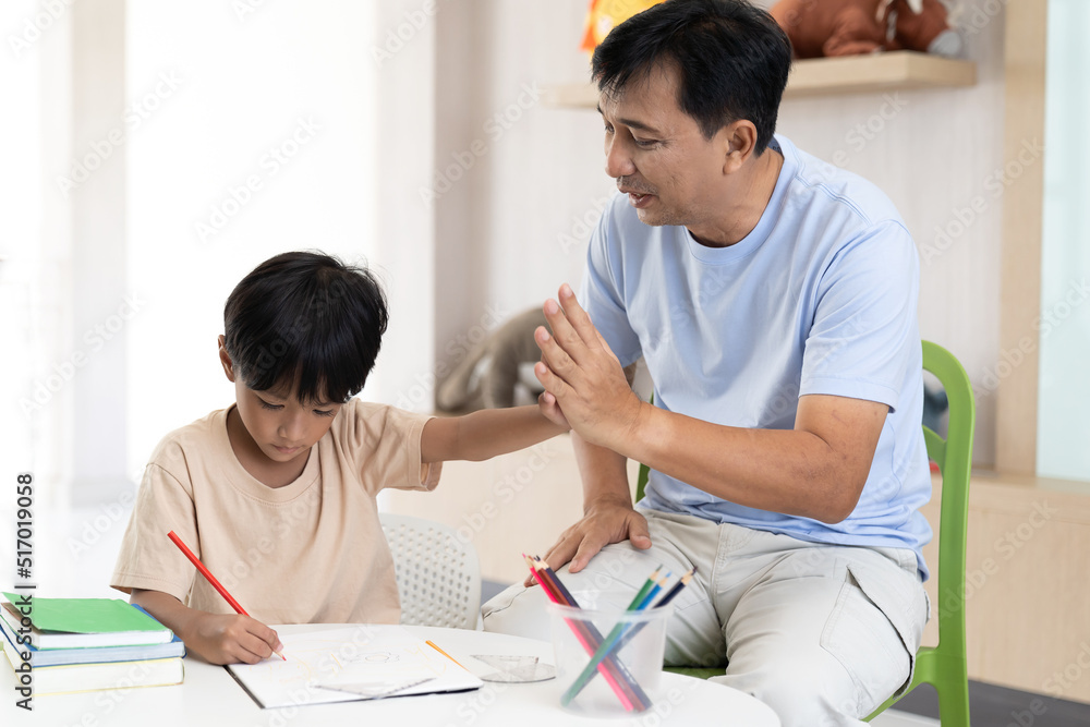 Asian little boy drawing on pages with colour pencils on table at classroom. Kid learning by drawing. Education concept Asian little boy drawing on pages with colour pencils on table at classroom. Kid learning by drawing. Education concept
