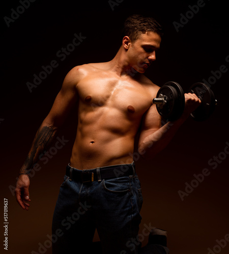 Bodybuilder training with dumbbells on black background. Rear view © qunica.com