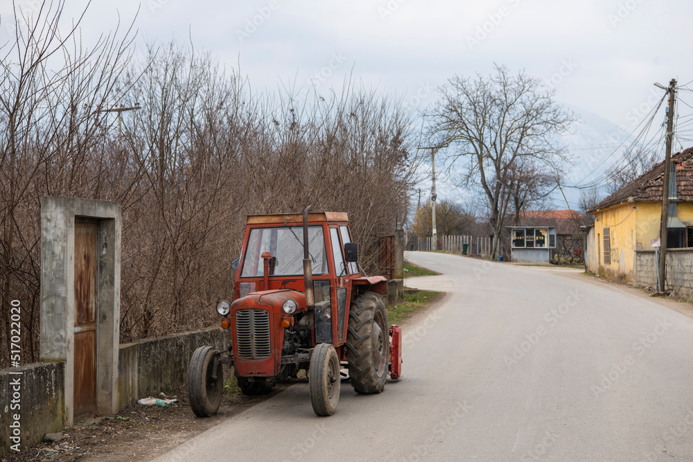 Old abandoned agriculture orange Tractor parked on countryside street. Old abandoned agriculture orange Tractor parked on countryside street.