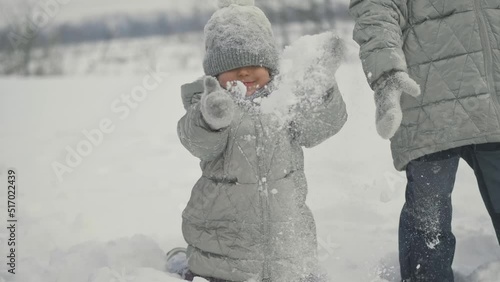 Funny little girl throws snow up to the sky and rejoices. Happy children play snowballs, run, throw snow. Funny kids play games indoors in the winter with snow