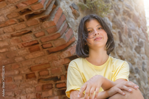Portrait of a young girl on the background of a stone wall with an arch. © Amerigo_images