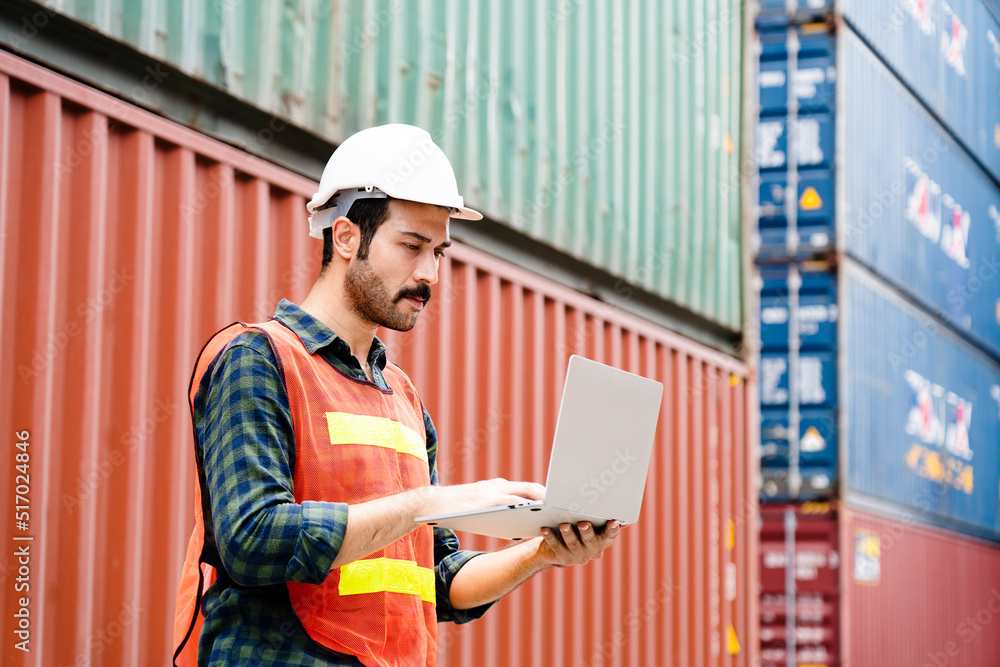 Container workers use laptops to work in port warehouses. Wear a hardhat to be safe at work. Container workers use laptops to work in port warehouses. Wear a hardhat to be safe at work.