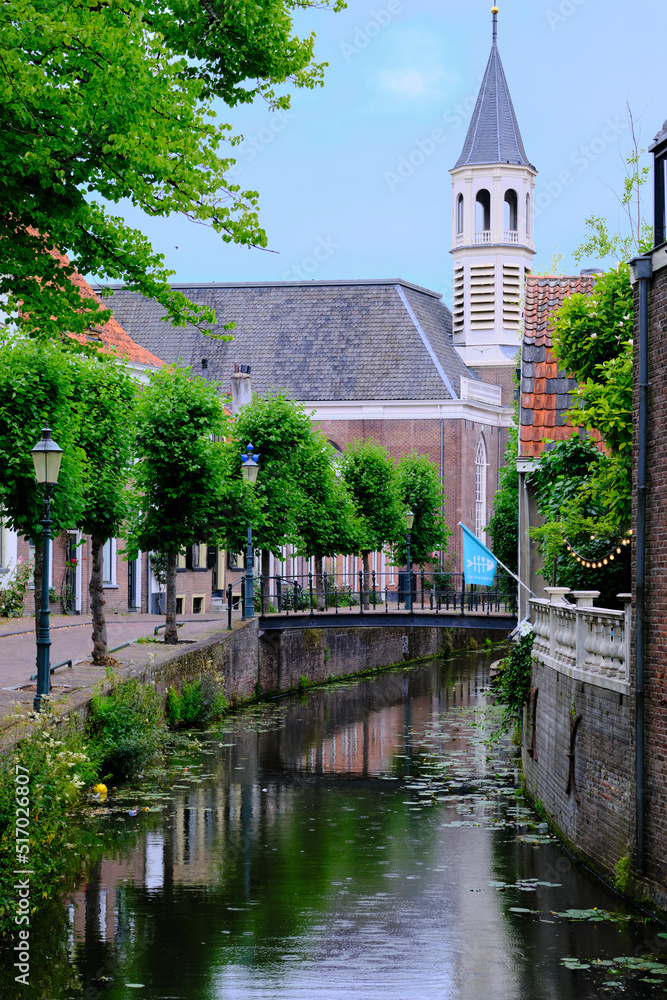 Amersfoort, The Netherlands, July 6, 2022. Langegracht Canal and Elleboogkerk church tower in the old city during the evening.