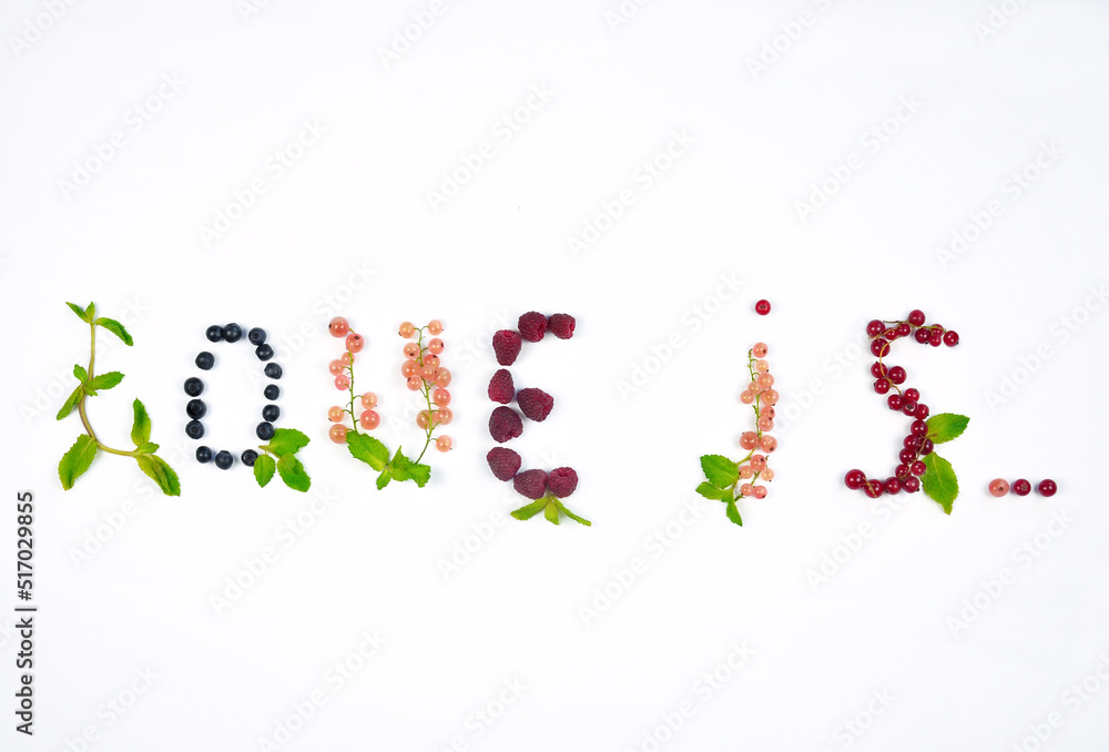 Words '' love is '' made from fresh summer berries and green mint leaves on white background. Top view, flat lay , free copy space. Words '' love is '' made from fresh summer berries and green mint leaves on white background. Top view, flat lay , free copy space.