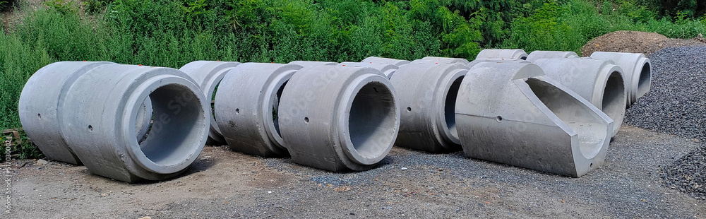 Wide photo of concrete sewage pipes in the park waiting to be put underground. They are sitting on the crushed stones. Wide photo of concrete sewage pipes in the park waiting to be put underground. They are sitting on the crushed stones.