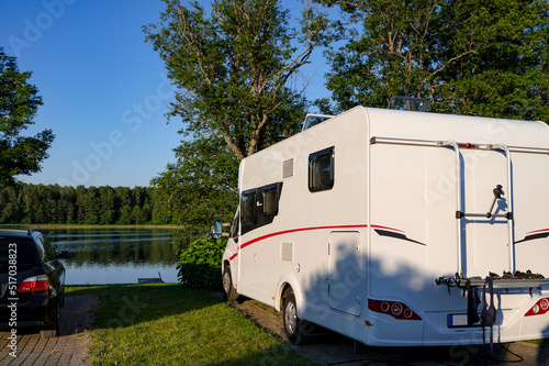 A sunny summer day. Camping. Parked caravan on country campsite. Shore of lake. Vacation.
