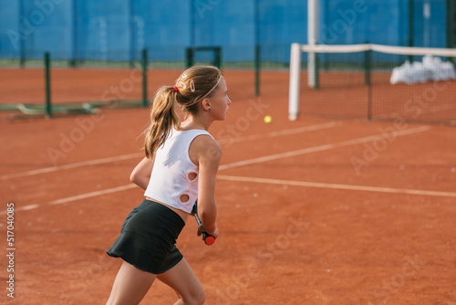 Girl in sportswear training for the competition on tennis court. © Nina