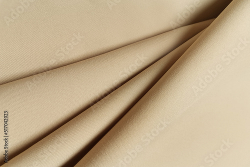 Beige crumpled or wavy fabric texture background. Abstract linen cloth soft waves. Gabardine wool fabric. Merino yarn. Smooth elegant luxury cloth texture. Concept for banner or advertisement.