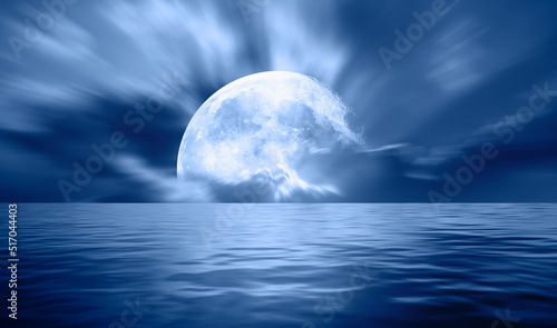 Night sky with blue moon in the clouds over the calm blue sea "Elements of this image furnished by NASA"