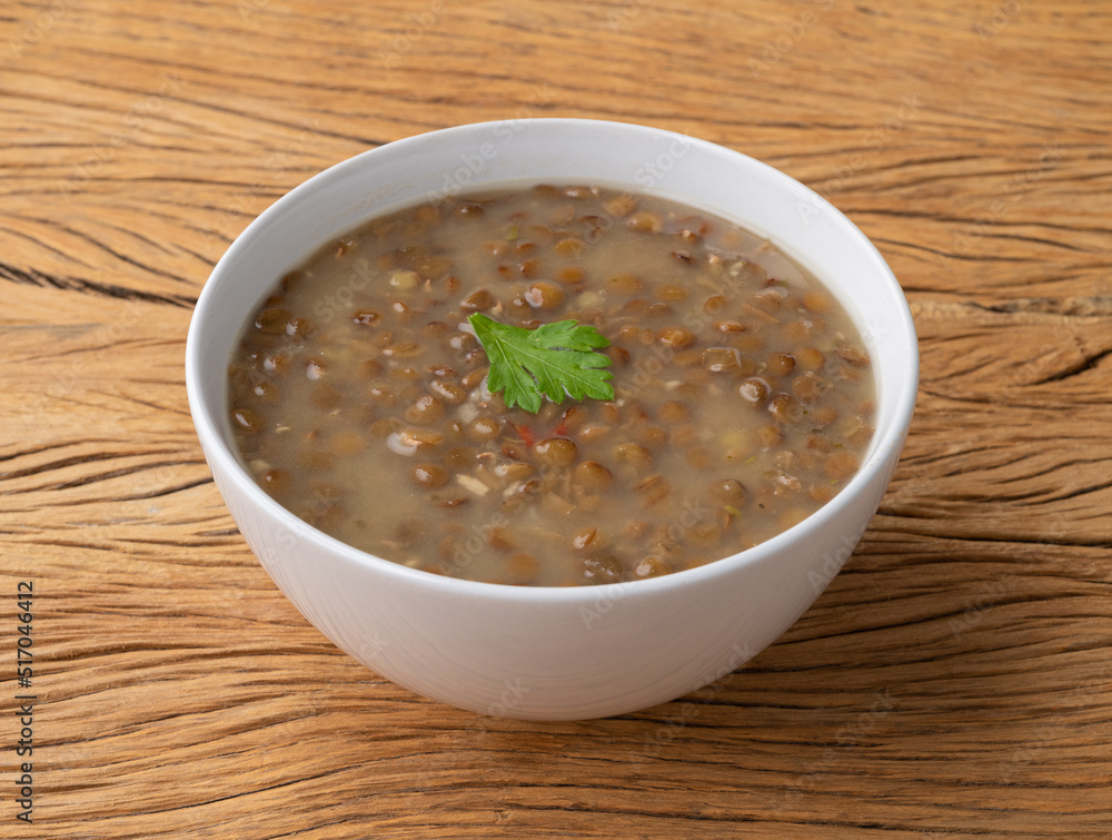 Lentil soup in a bowl with seasoning over wooden table