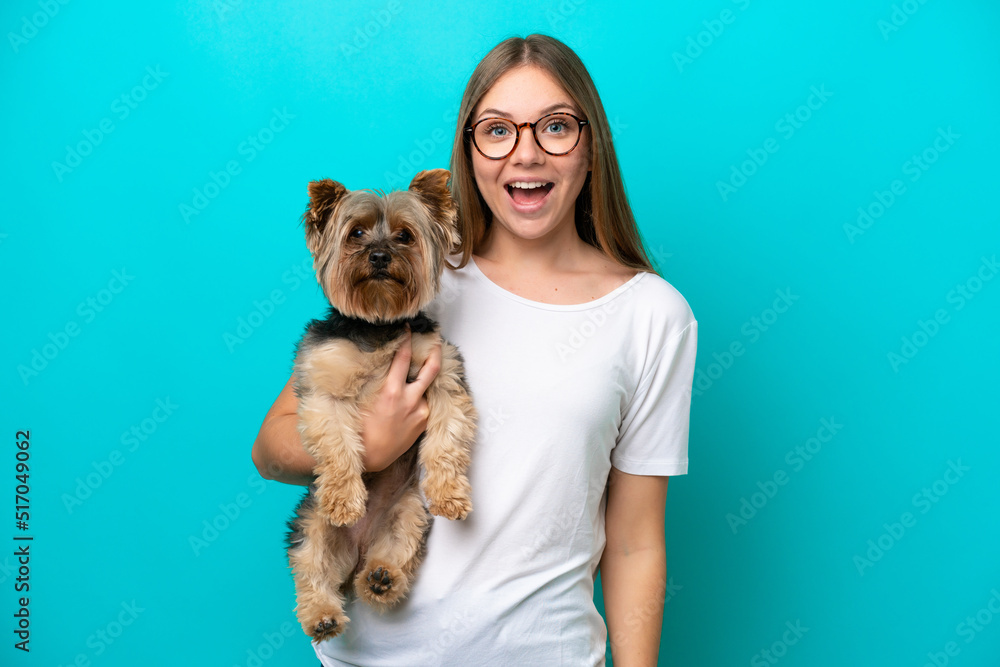 Obraz premium Young Lithuanian woman holding a dog isolated on blue background with surprise and shocked facial expression